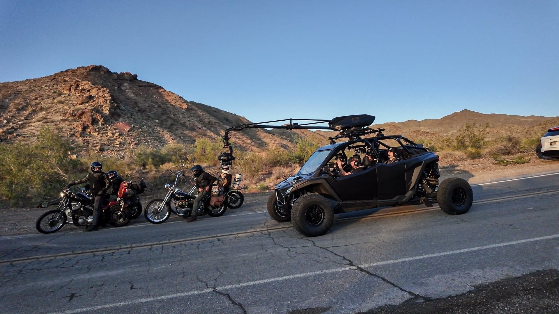 Riders and a camera car rolling down a desert highway at golden hour