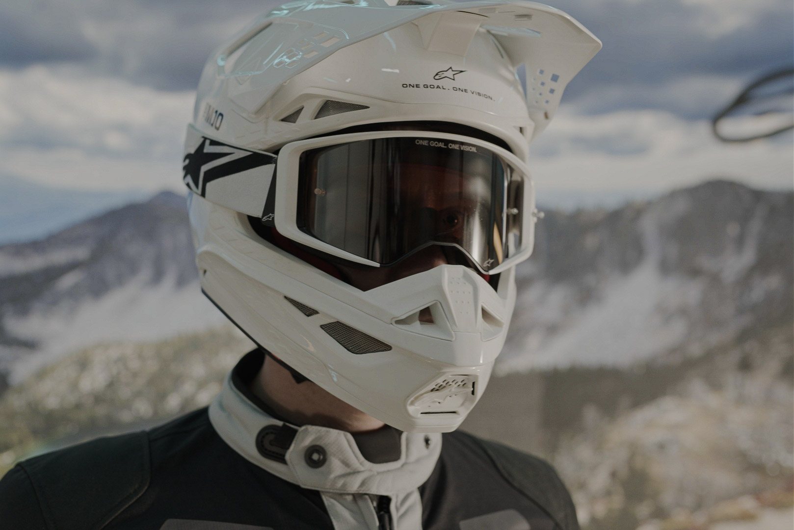 Rider in a white helmet and goggles against desert mountains