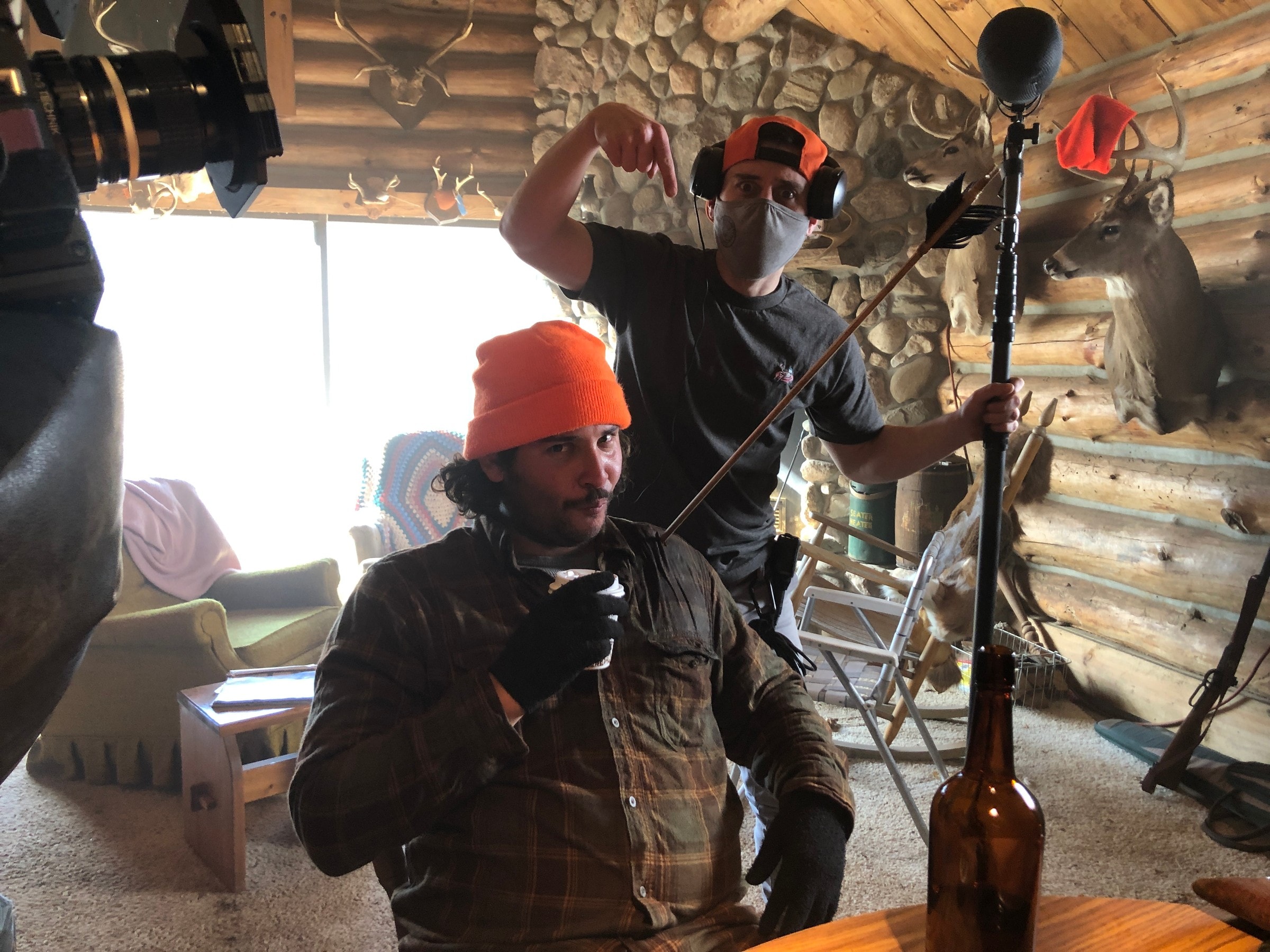 Boom op clowning behind an actor in an orange beanie on the cabin set