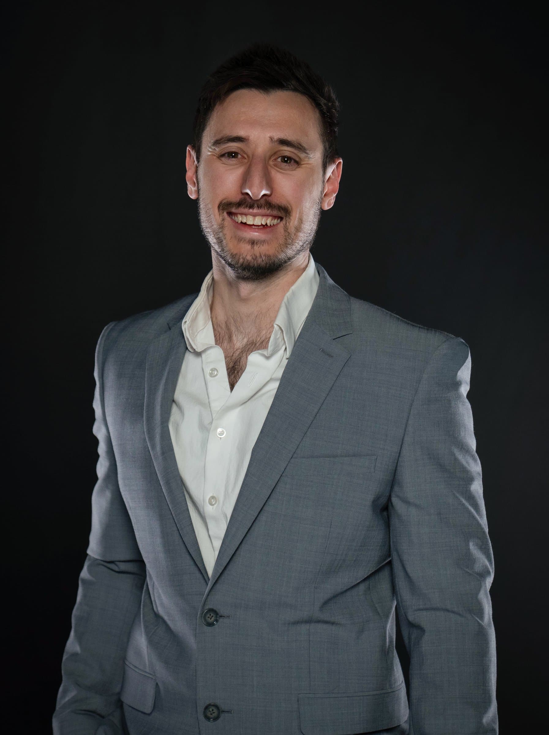 Garrett Krumpe in a grey suit against a black backdrop