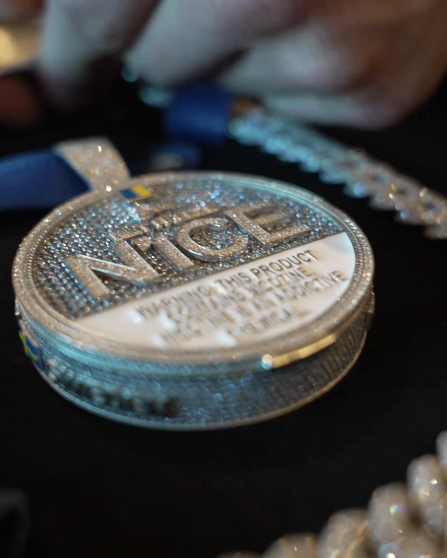 Iced-out N1CE tin pendant in its presentation case