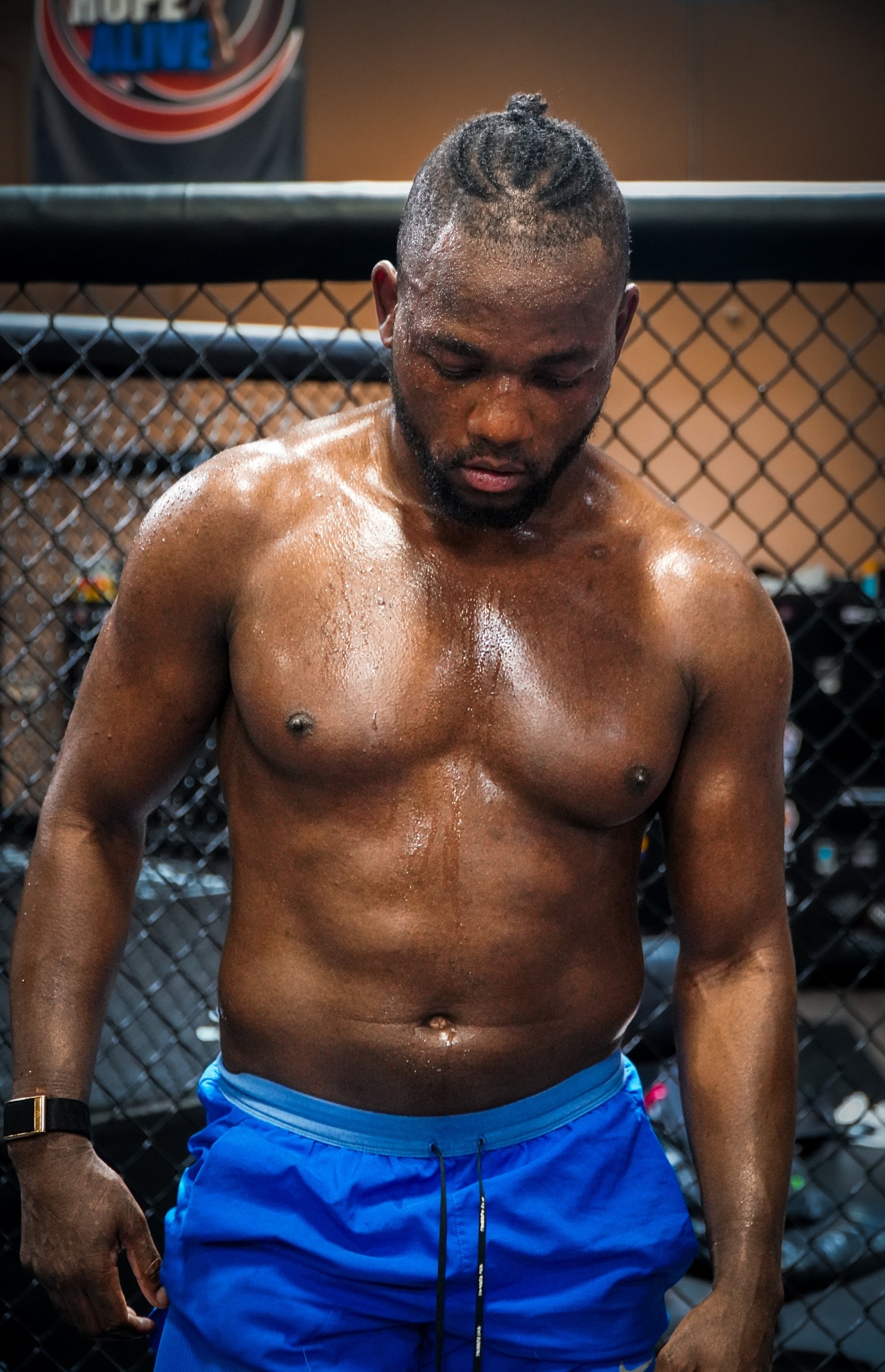 Manel Kape shirtless in the cage after training, head down