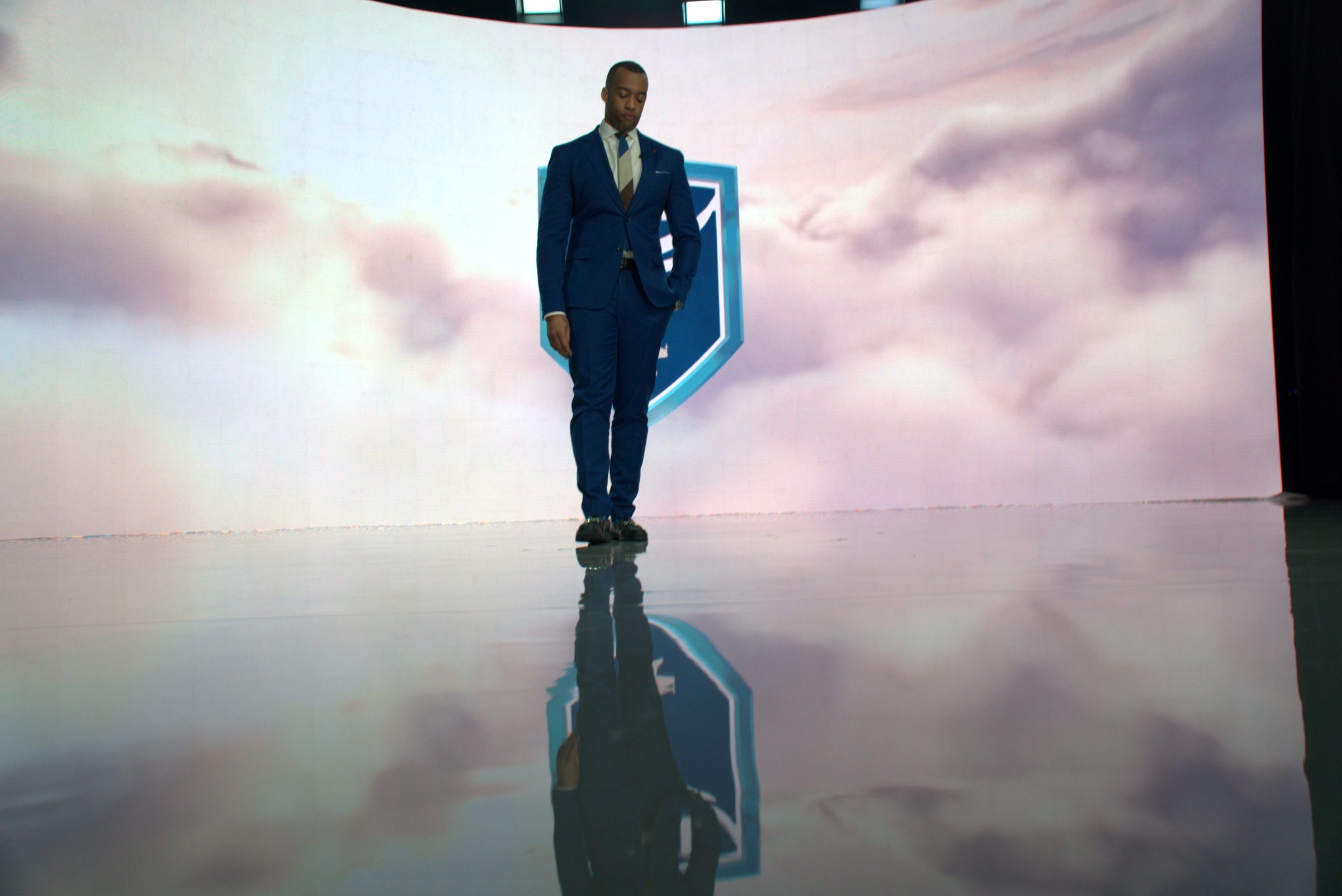 Wide of the host standing on the reflective XR stage floor