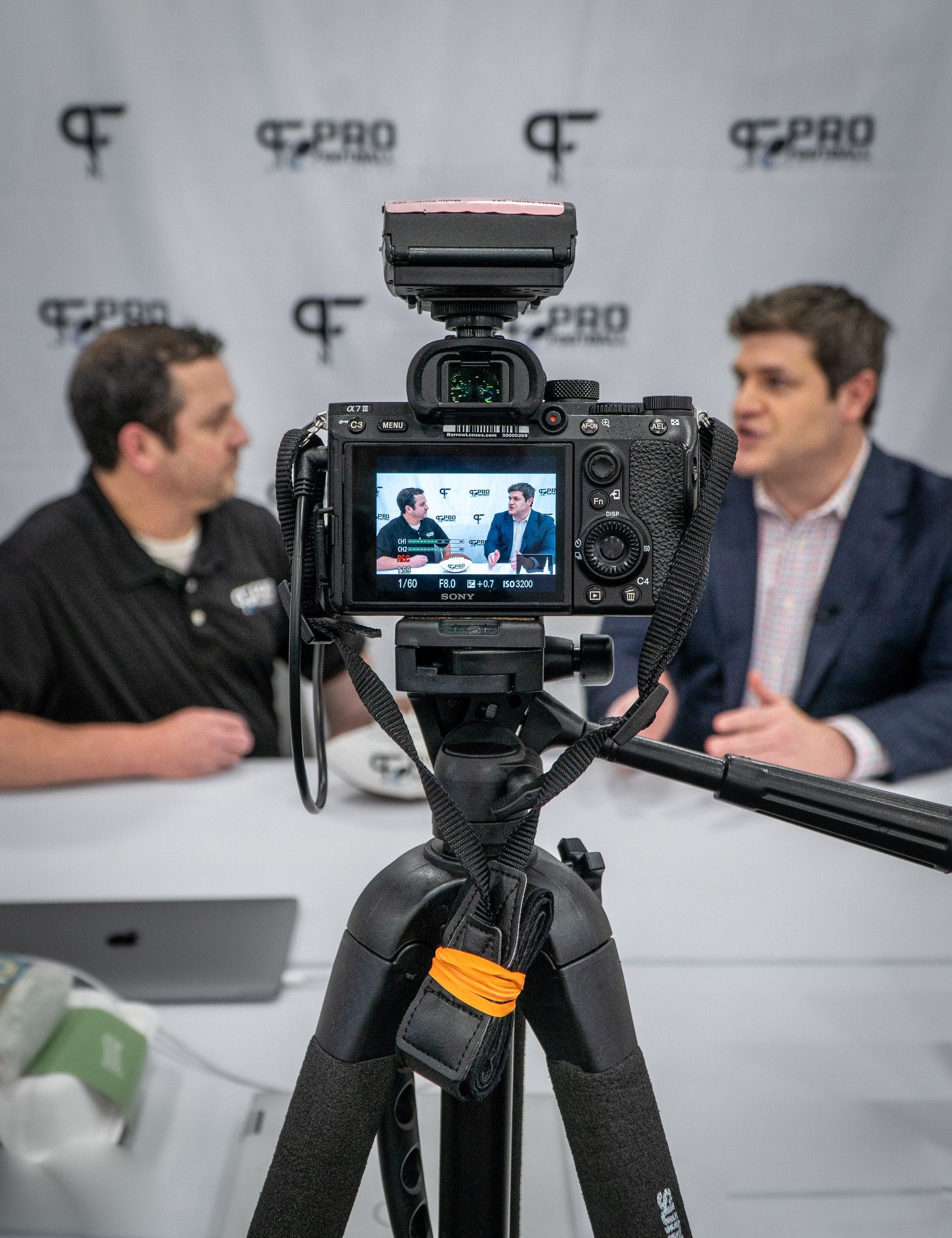 Camera on sticks recording a two-person sit-down on Radio Row